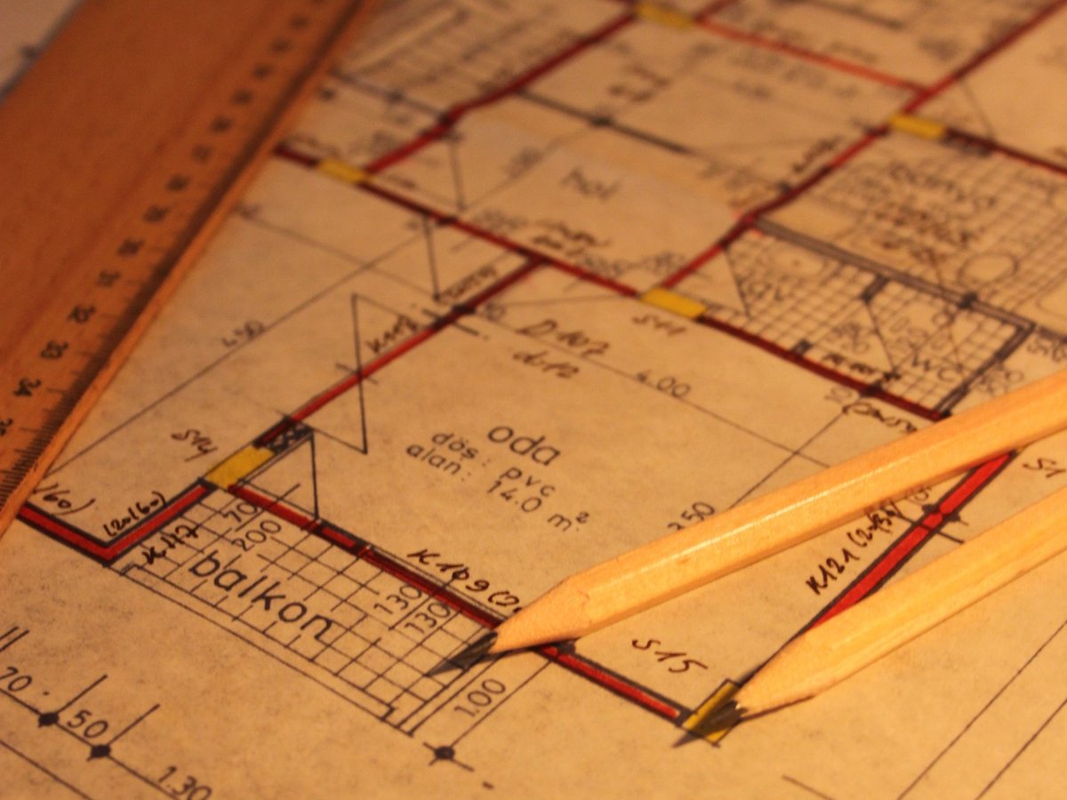 Plan de logement ancien annot&eacute; &agrave; la main, avec crayons et r&egrave;gle pos&eacute;s dessus