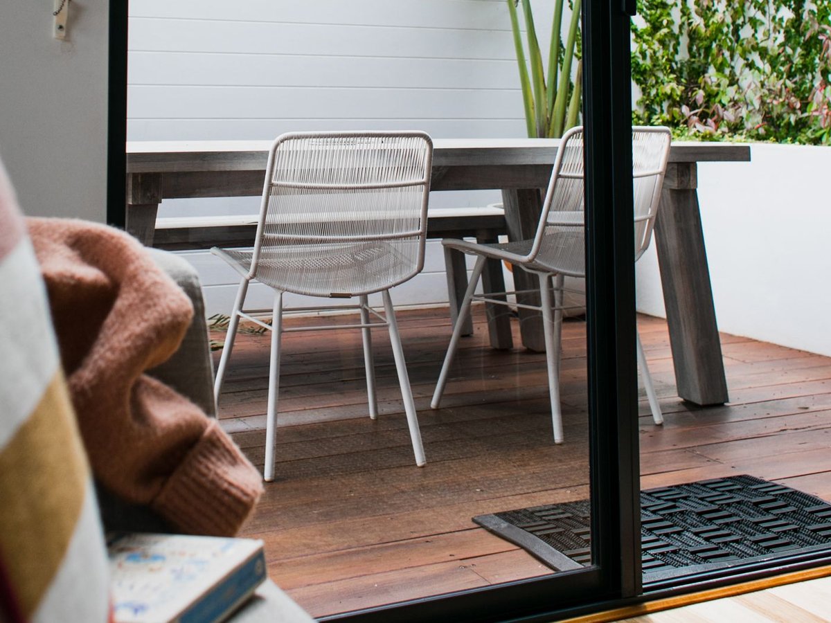 Terrasse en bois de plain-pied dans le prolongement d'un s&eacute;jour, vue depuis la baie vitr&eacute;e