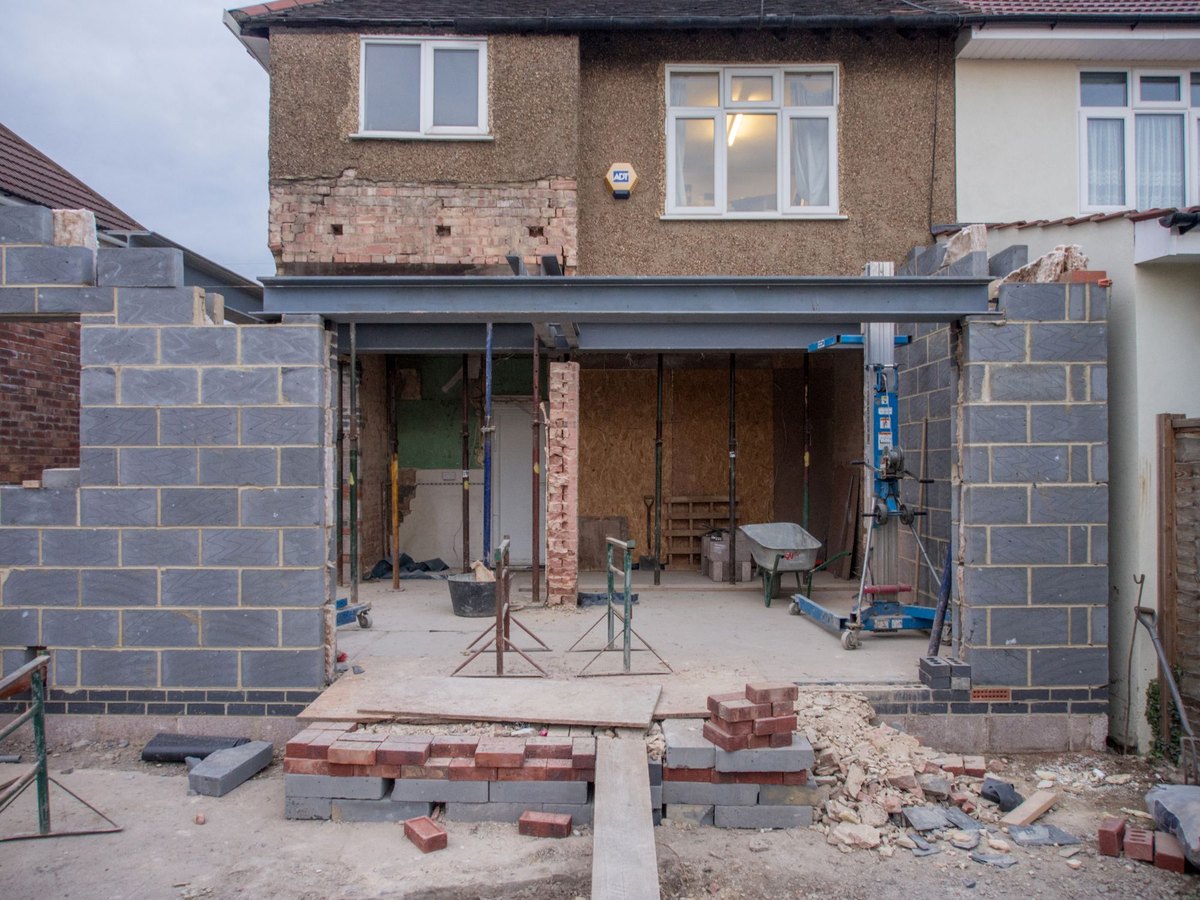 Extension de maison en blocs de b&eacute;ton en cours de construction, accol&eacute;e &agrave; la fa&ccedil;ade arri&egrave;re